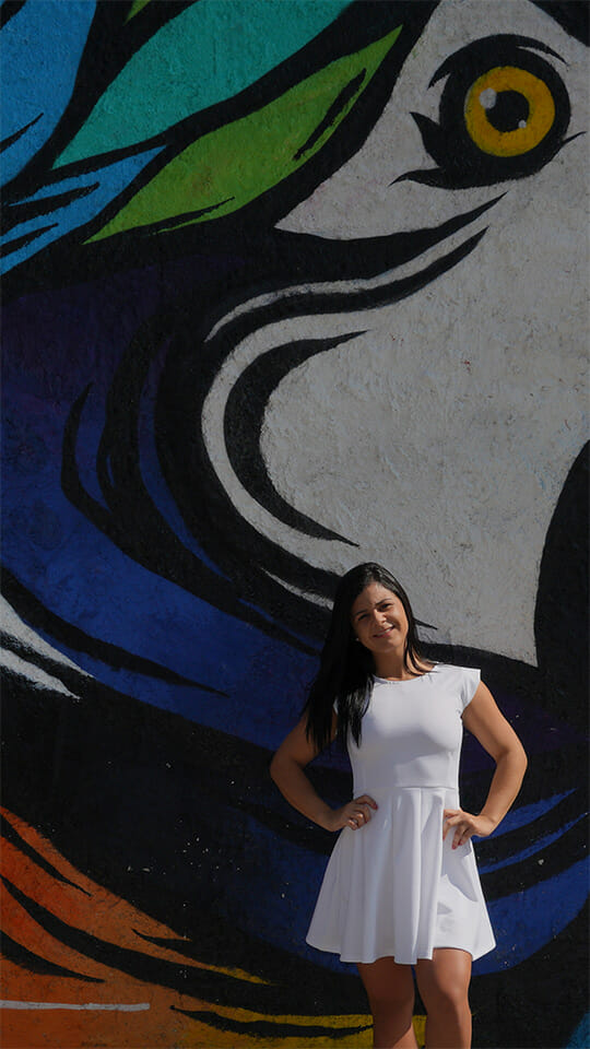 Menina em frente ao muro com grafite de vestido branco - Arte urbana