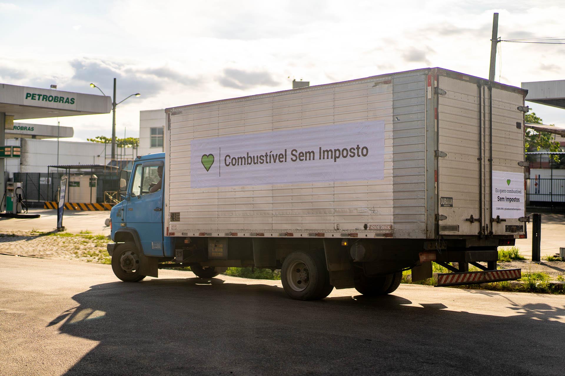 Caminhão bau azul com adesivo de 4m do Movimento Combustivel Sem Imposto - Mercado São Sebastião