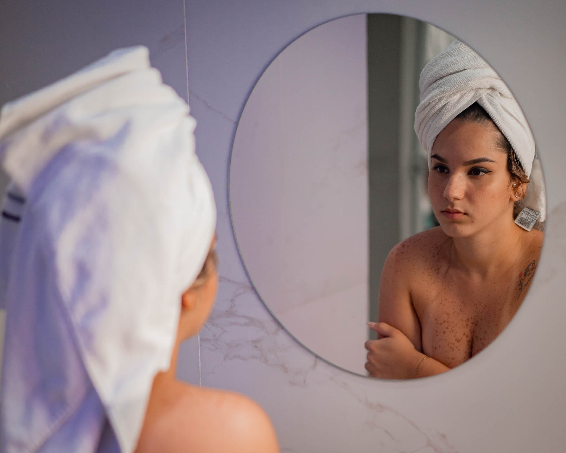 mnodelo seminua em ensaio fotografico sensual em frente ao espelho do banheiro com toalha branca na cabeça