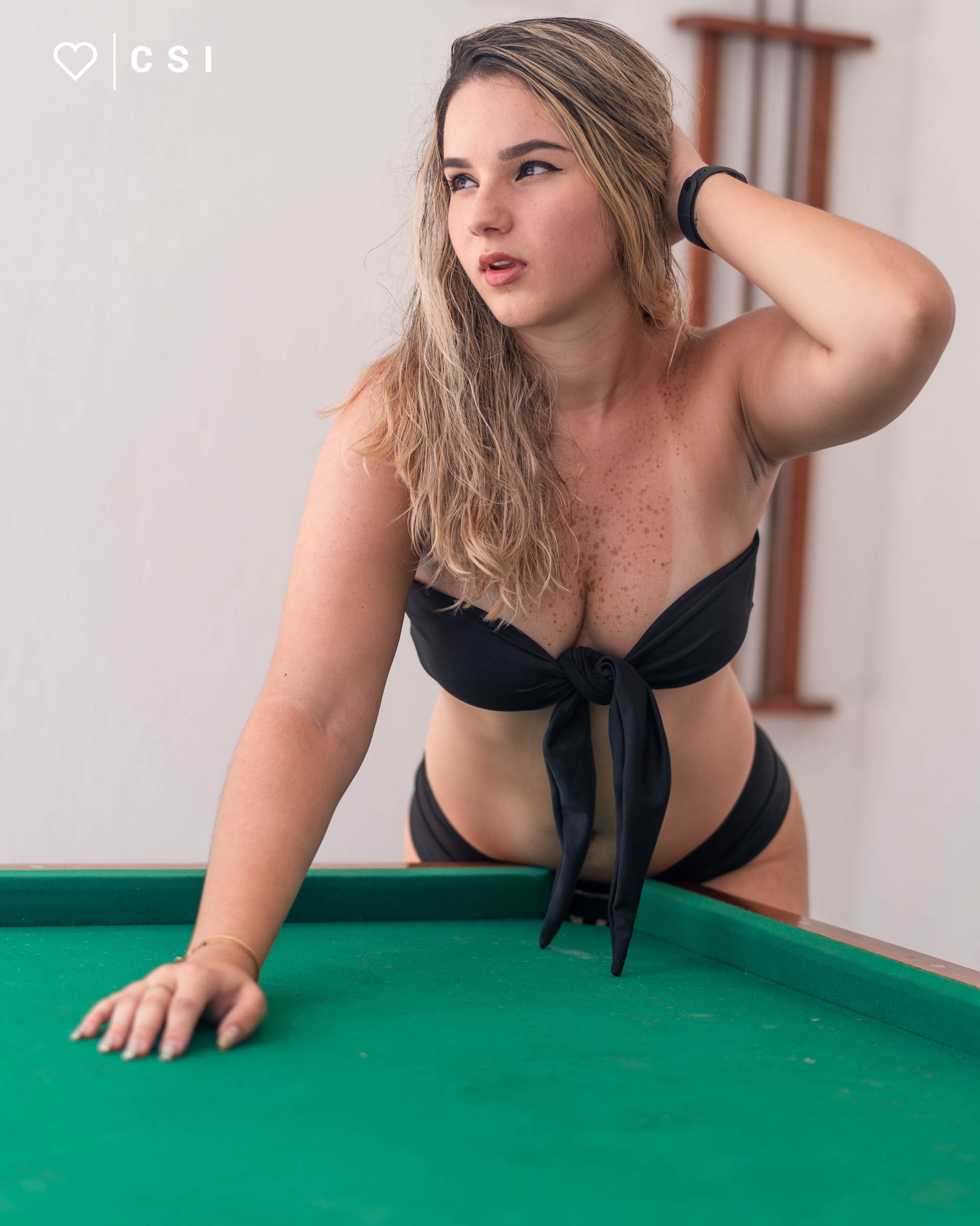 modelo em ensaio fotografico sensual com look preto e escarpin salto fino na mesa de sinuca verde
